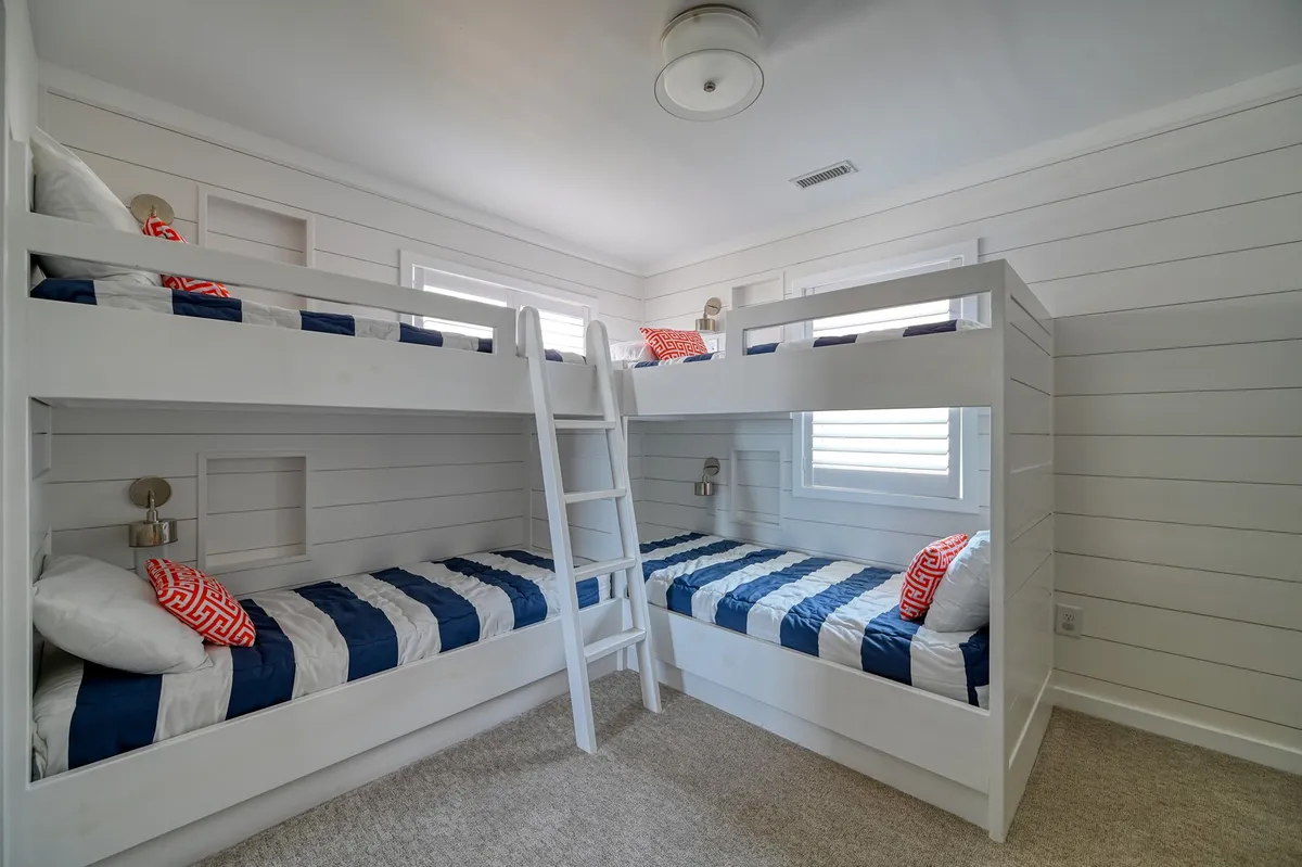 A playful bunk room setup with two bunk beds featuring striped bedding and decorative cushions. The space looks comfortable and fun, ideal for kids to sleep, play, and unwind together.