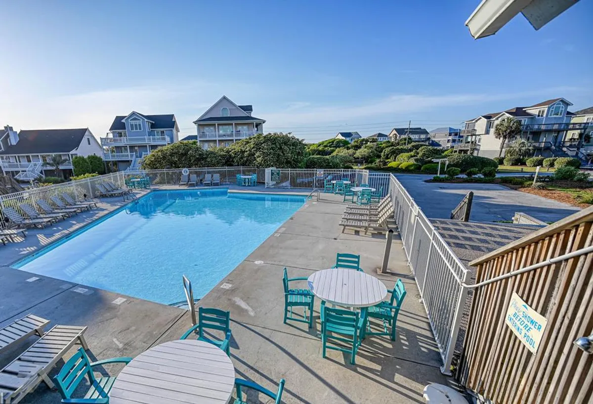 A sparkling community swimming pool is the focal point, surrounded by comfortable outdoor seating and mature greenery. The setting is peaceful yet lively, with the pool designed for both leisure and active use. The image hints at group activities and seasonal enjoyment.